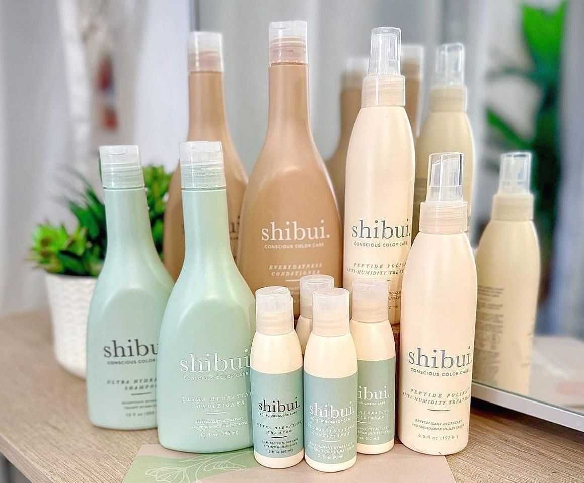 Assorted Shibui hair care products displayed on a table with plants in the background.