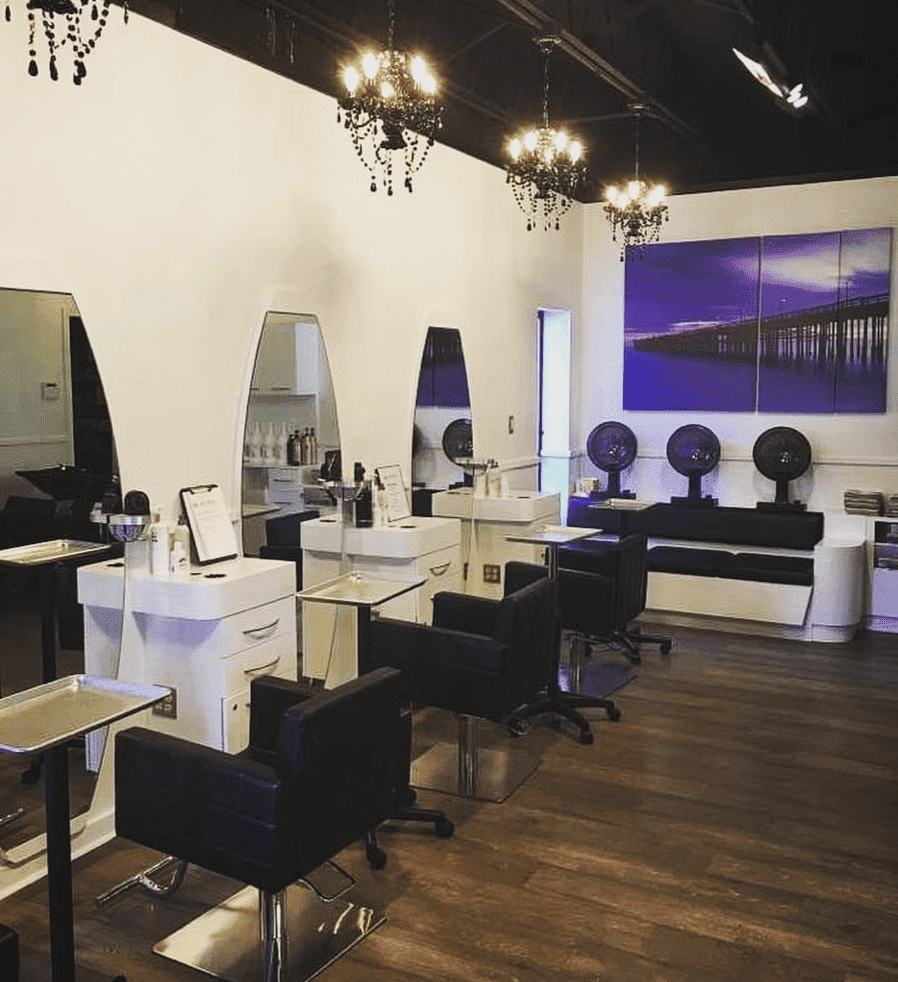 Modern salon interior with styling stations and chandeliers.