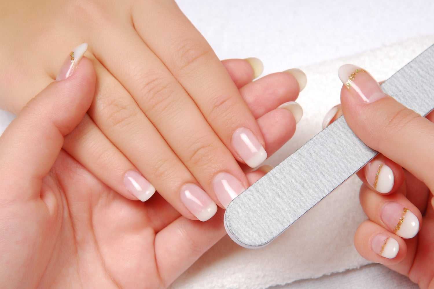 Close-up of a manicure session with hands being filed and polished with a nail file.