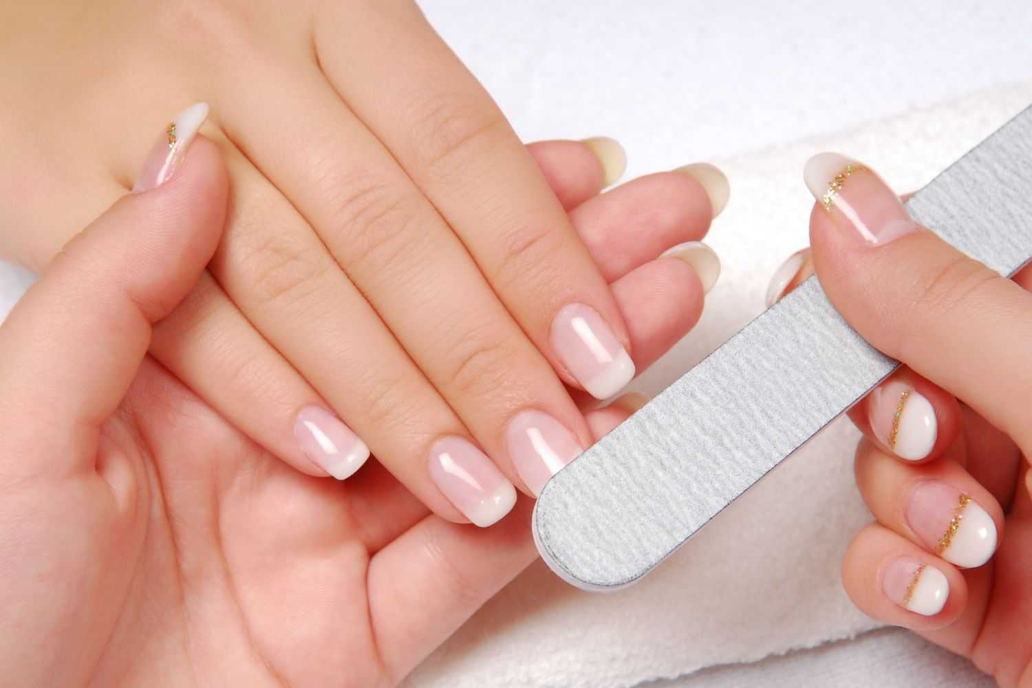 Close-up of a manicure session with hands being filed and polished with a nail file.