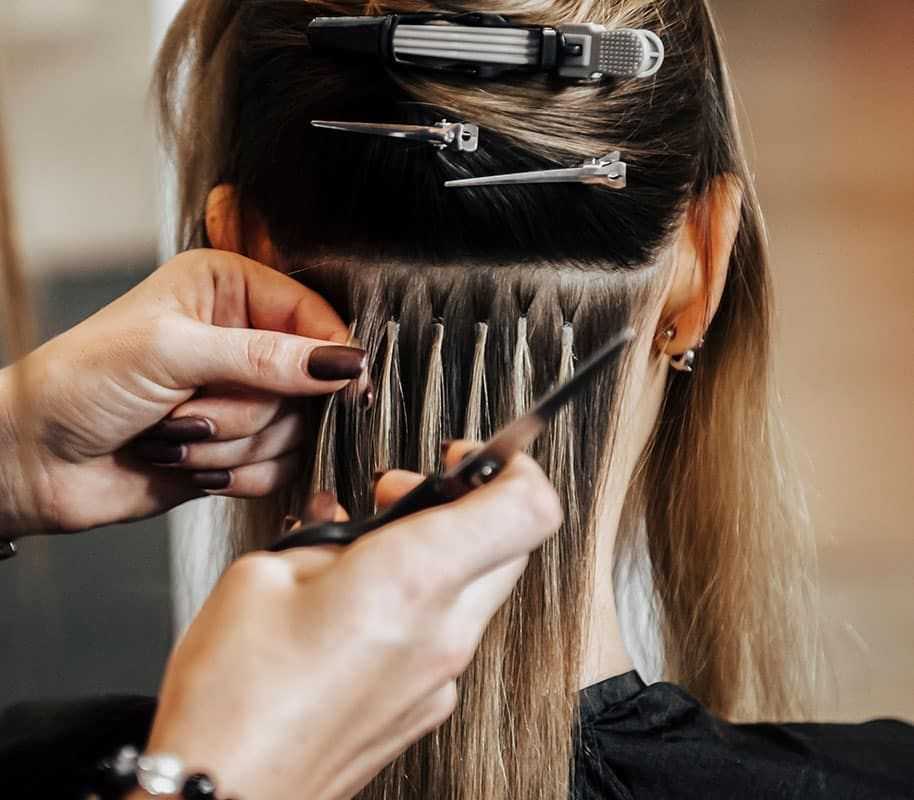 Stylist adding hair extensions to a client's hair using a clip-in method.